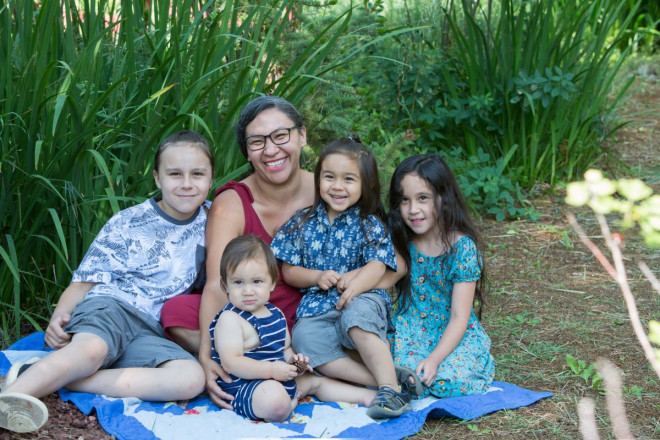A mama and her children sitting on a star quilt in Arroyo Seco, NM