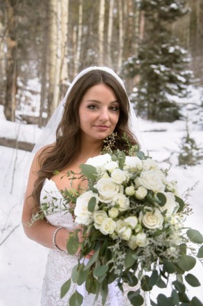 Kiersten holds her cascading white roses which perfectly match the snow and ponderosa pines