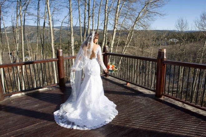 Alysa holds her veil and bouquet during a picture of the back of her wedding dress