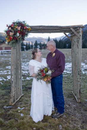 Celeste and Joe in front of autumn altar with mountain views