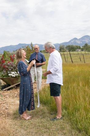 Bride and groom laugh at their small wedding ceremony as bride pulls out her vows in a scroll