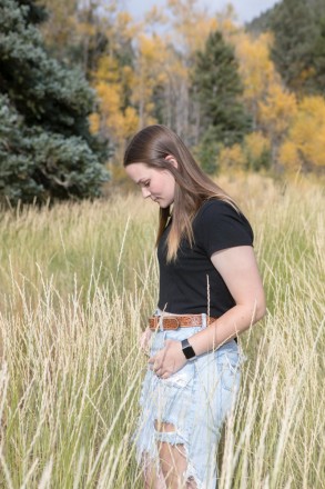 High school senior, Katie, shows her beautiful profile while standing in tall grass by aspen trees