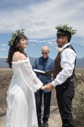 Mackenzie and Steven listen to their officiant read a crown ceremony which he wrote for them