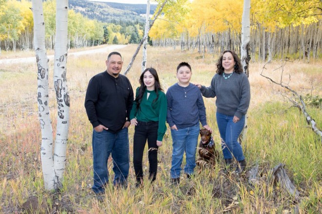 Family poses with dog in yellow aspens in Angel Fire