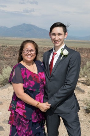 Groom, Dustin, has a photo taken with his mon with the mountains behind them
