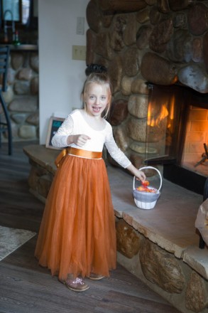 The flower girl, dressed in orange, warms up in front of the fire