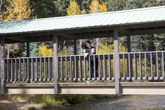 High school senior looks down at the Red River while standing on covered bridge