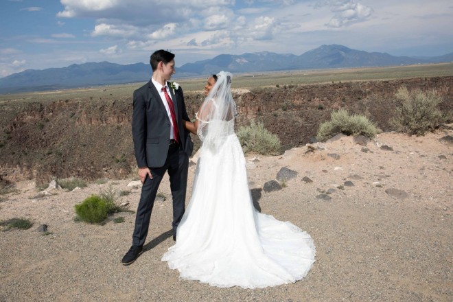 Tall groom and his shorter bride with the Rio Grande gorge and Sangre de Cristo mountain range