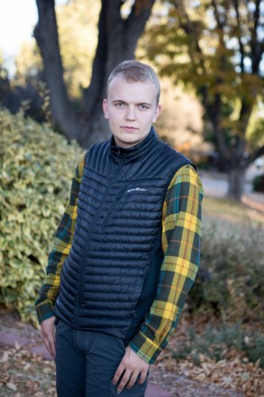 High school senior wearing plaid and down vest with autumn foliage