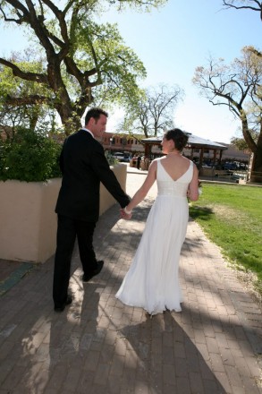 Bride and groom walk hand in hand through the Taos plaza after their New Mexico wedding