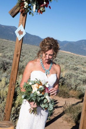 Chasity with a turquoise squash blossom, looks at her wedding bouquet