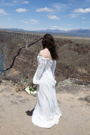 In her off-the-shoulder wedding dress, Mackenzie watches and listens to the Rio Grande river flowing below.