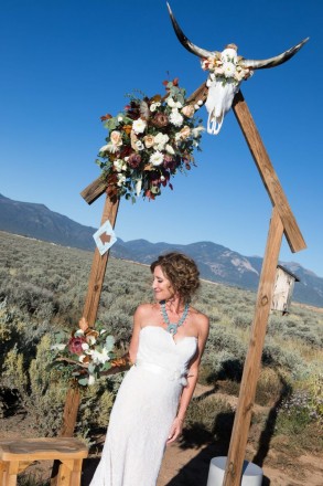 Chasity smiles at her wedding bouquet, made by Enchanted Florist in Taos