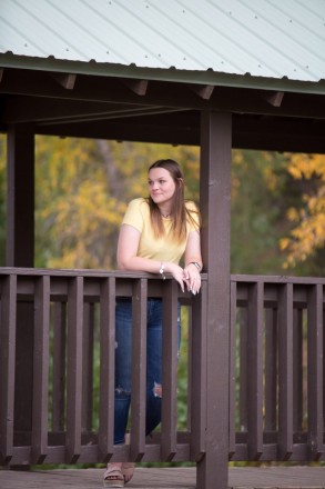 Katie stands under covered bridge with gorgeous yellow aspens in background