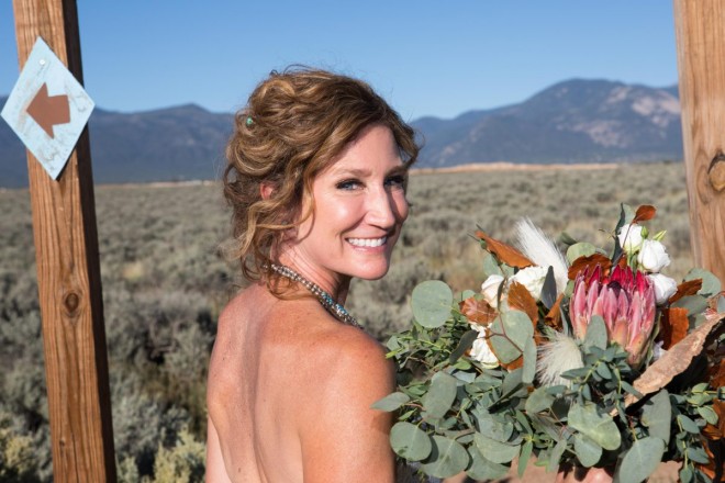 Chasity poses with her wedding bouquet with Taos mountains in the background