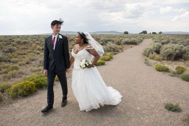 Newlyweds walk on Taos Mesa as the spiderplant blooms in July