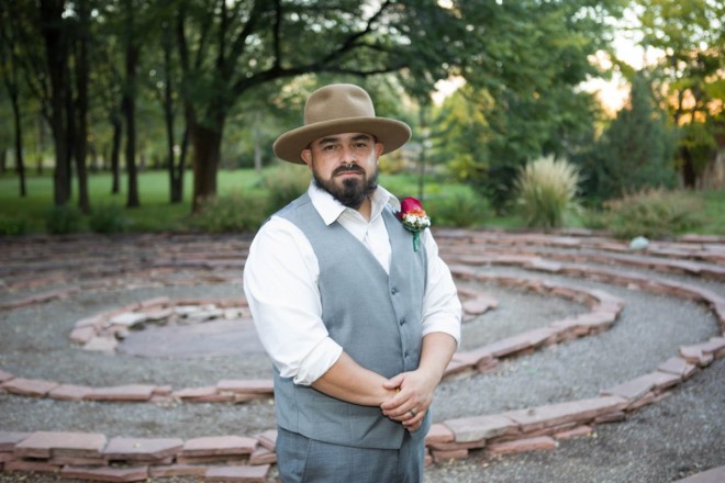 Groom, Edwardo, stands in front of the labyrinth at Adobe and Pines