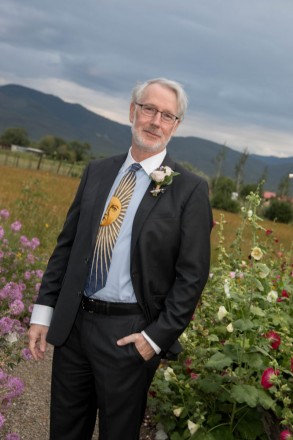 Groom with sunshine tie and gardens with hollyhocks and a meadow