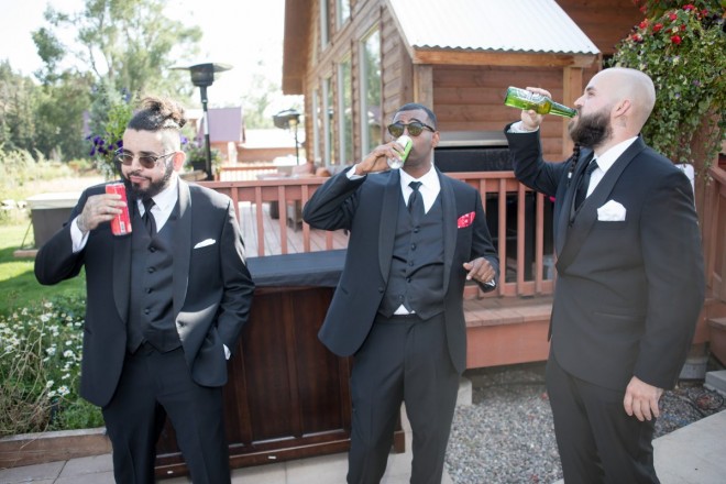 Groomsmen drink beverages in a funny pose before the wedding ceremony begins.