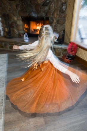 The flower girl shows off her orange dress with a spin