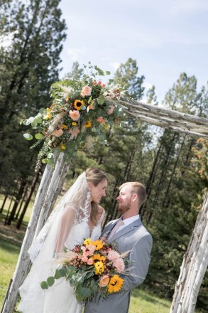 Jade and Brannon pose with their gorgeous airy bouquet and altar flowers