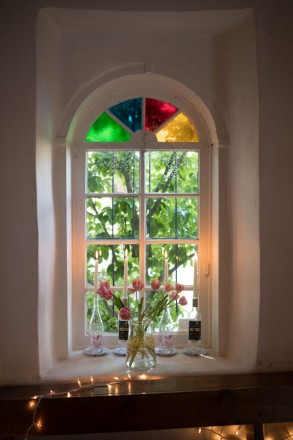 A window at The Love Apple with old stain glass and fresh flowers