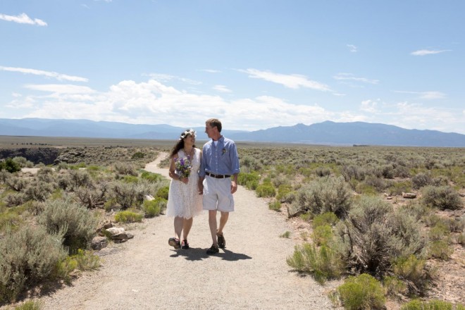 Keri and Robert and smiling and happy as they walk away from their west rim wedding site in Taos.
