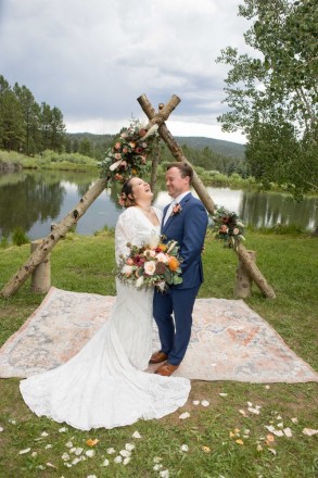 A bohemian-style wedding with a rug by a pond in Taos Canyon