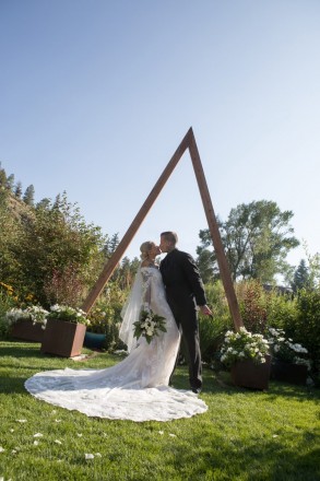 Beautiful triangle arch with bride and groom kissing in late afternoon