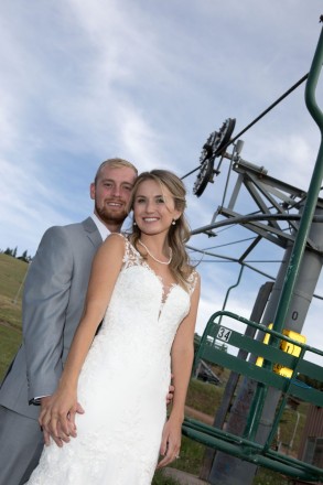 Arizona couple pose with the ski resorts chair lift at their destination mountain wedding