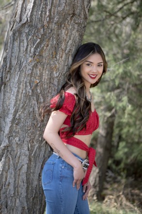With a red shirt, blue jeans, and red lipstick, Jenica poses in her first outfit for her senior photos