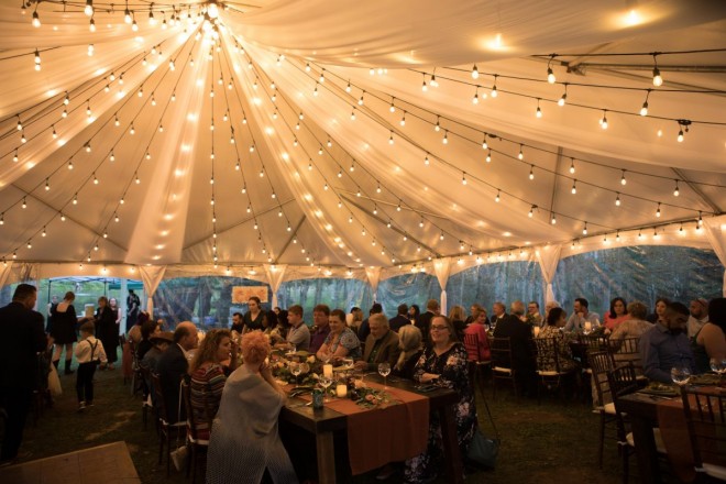 While it rains outside, dinner is served inside the wedding tent in Taos Canyon