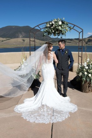 Israel and Victoria pose with their wedding altar after their outdoor October ceremony