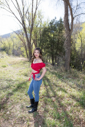 Jenica, part of Penasco graduating class of 2022, smiles with her hand on her hip in Taos Canyon