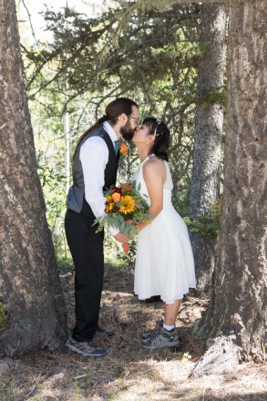 Sarah and Michael have a wedding day kiss between Ponderosa Pines