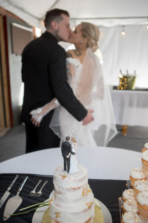 Bride and groom kiss and grab butts, modeling after their wedding topper