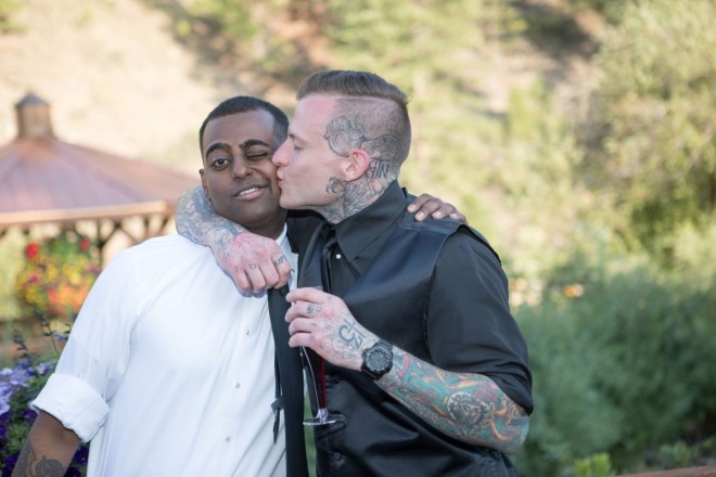Groom with many tattoos kisses best man at South Fork wedding