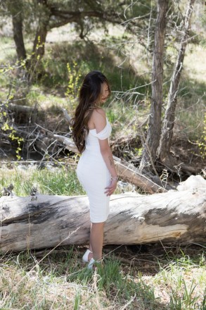 Jenica stands in elegant white dress for her senior photos in Taos