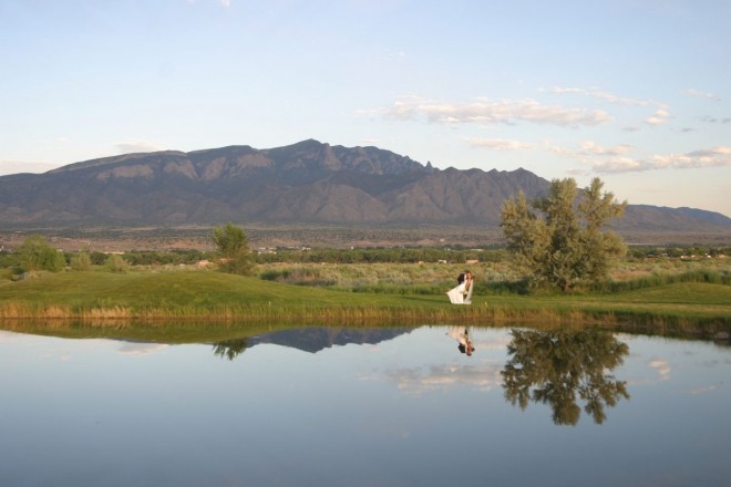Wedding dip at sunset in front of pond with Sandia mountains in background
